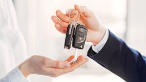 Na imagem aparece duas mãos, de uma pessoa entregando chave de carro para outra pessoa.