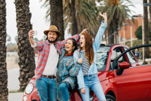 cheerful people taking selfie near red car street