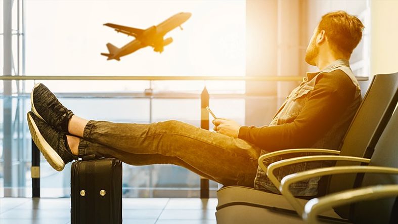 homem sentado no aeroporto olhando o avião da janela 