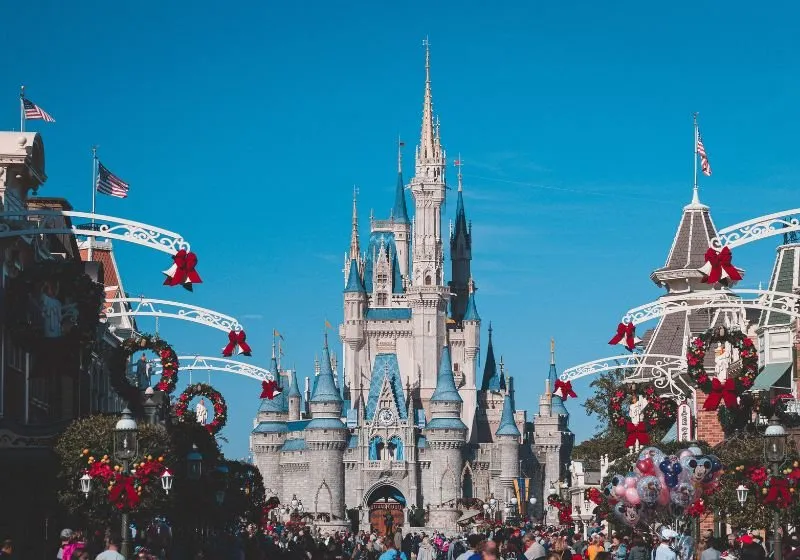 castelo da Disney em Orlando com varias pessoa e arvores em baixo
