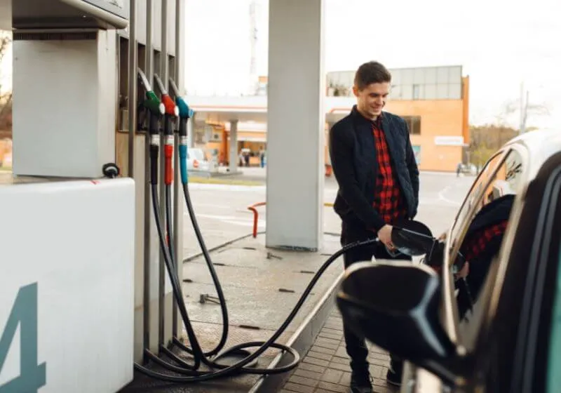 homem feliz em um posto de gasolina colocando combustivel em um carro