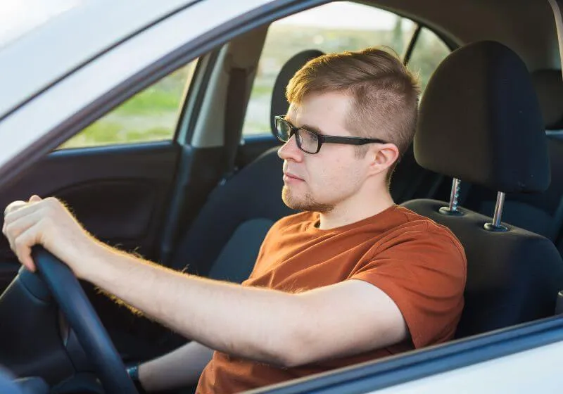 homem de óculos dirigindo em um carro alugado 