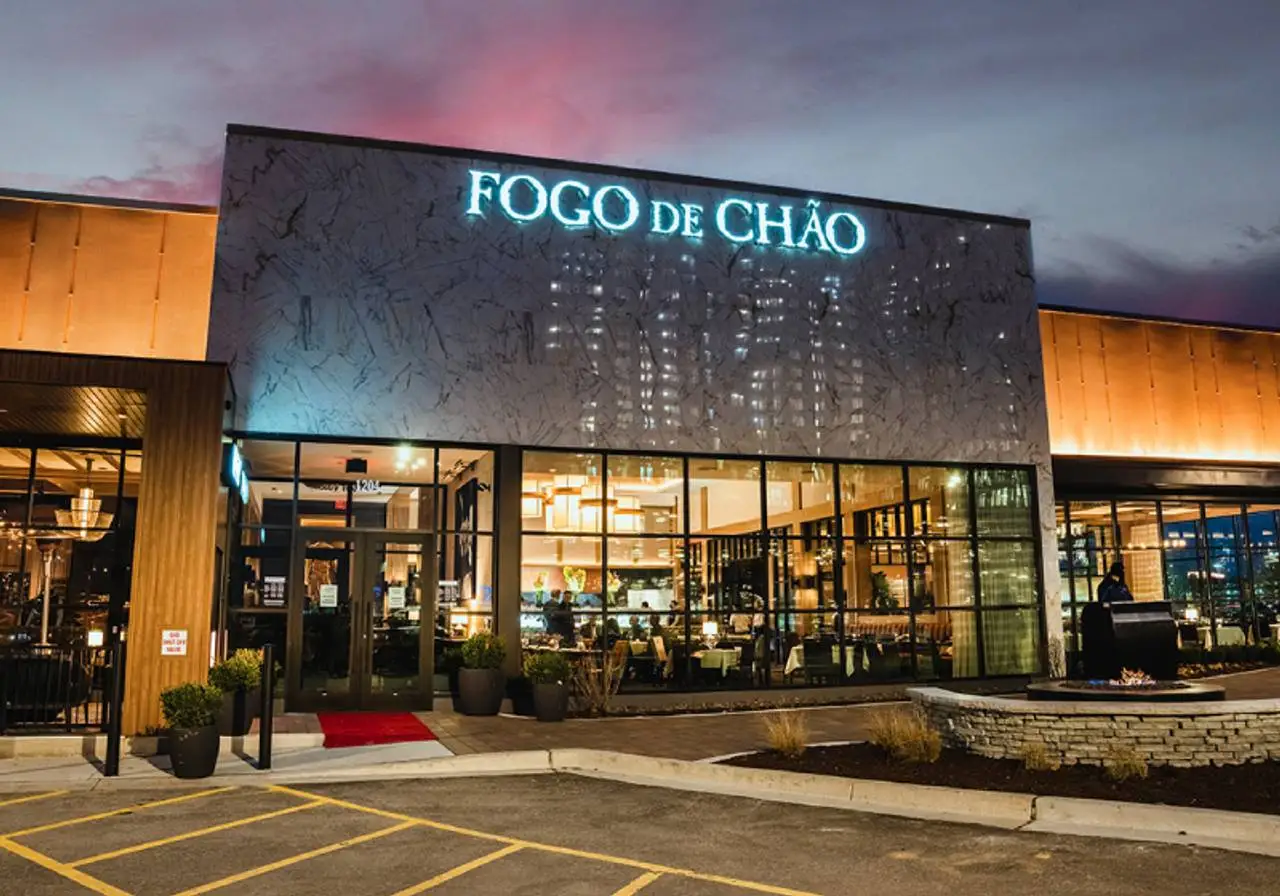 Fachada noturna do Fogo de Chão, uma churrascaria brasileira com arquitetura moderna e interior vibrante, um destino culinário em viagens.