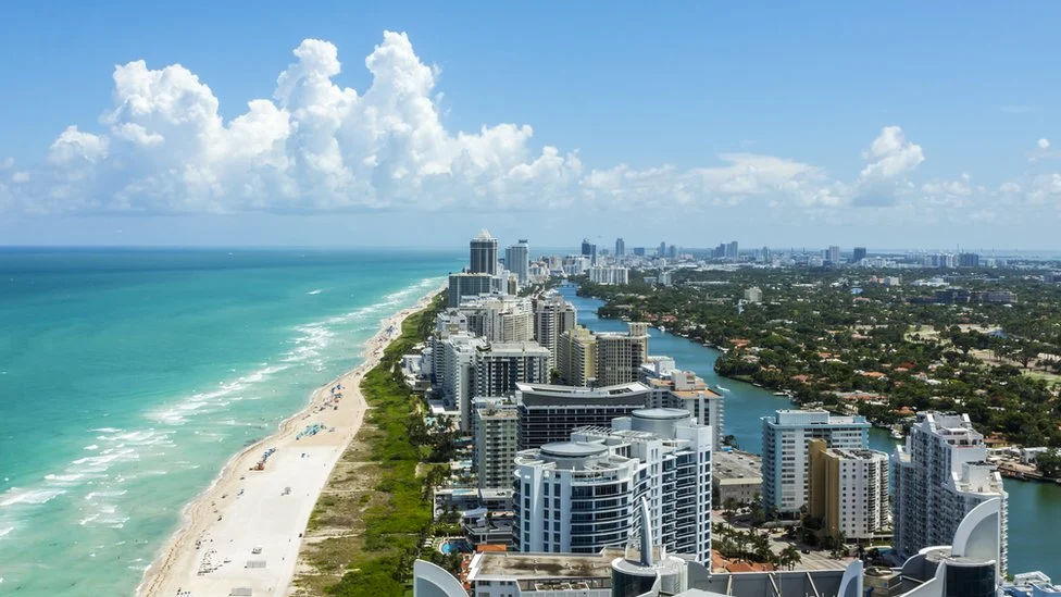 Vista aérea de Miami Beach, Flórida: longa praia, mar turquesa, arranha-céus modernos à beira-mar e canais internos. Destino ideal para viagens e férias.