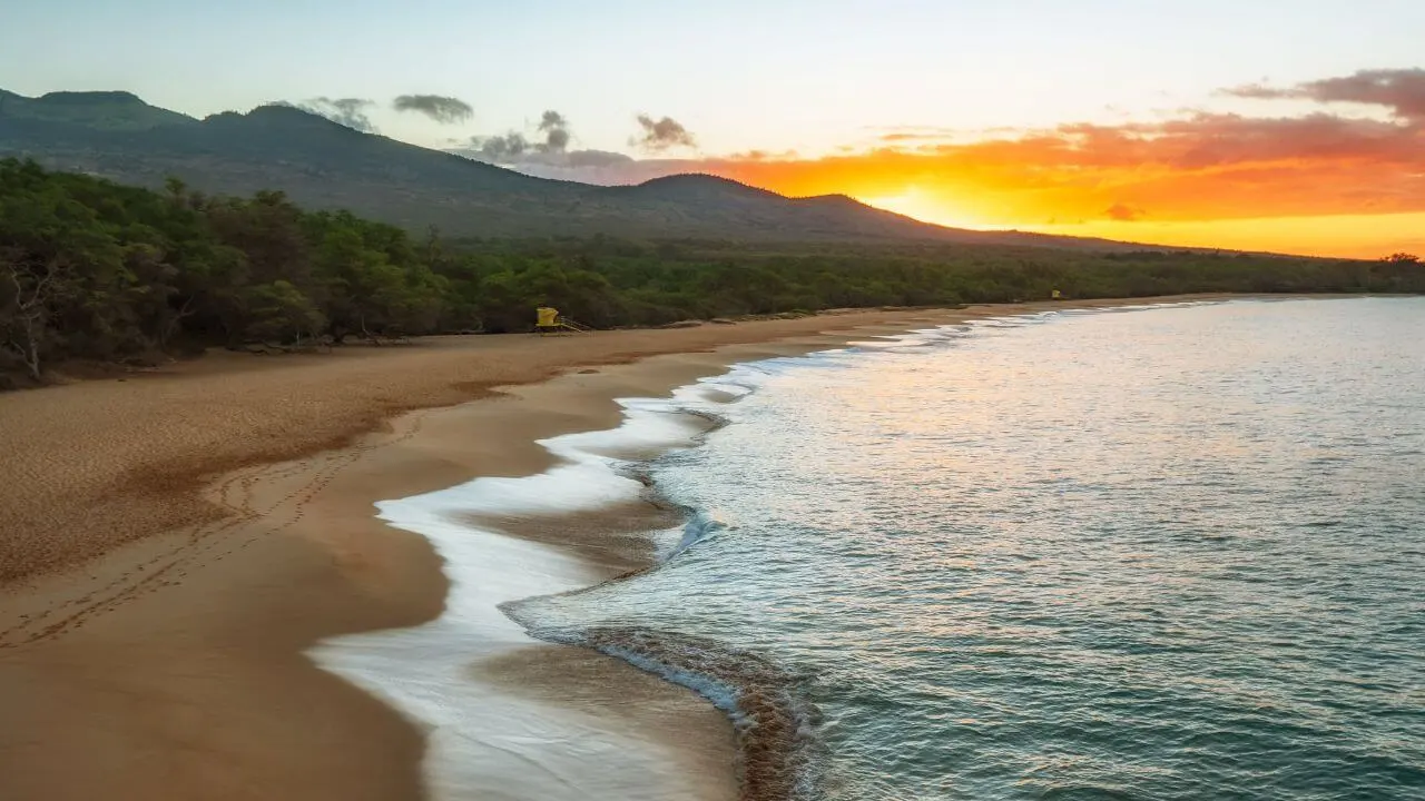 Por do sol na praia com montanha ao fundo