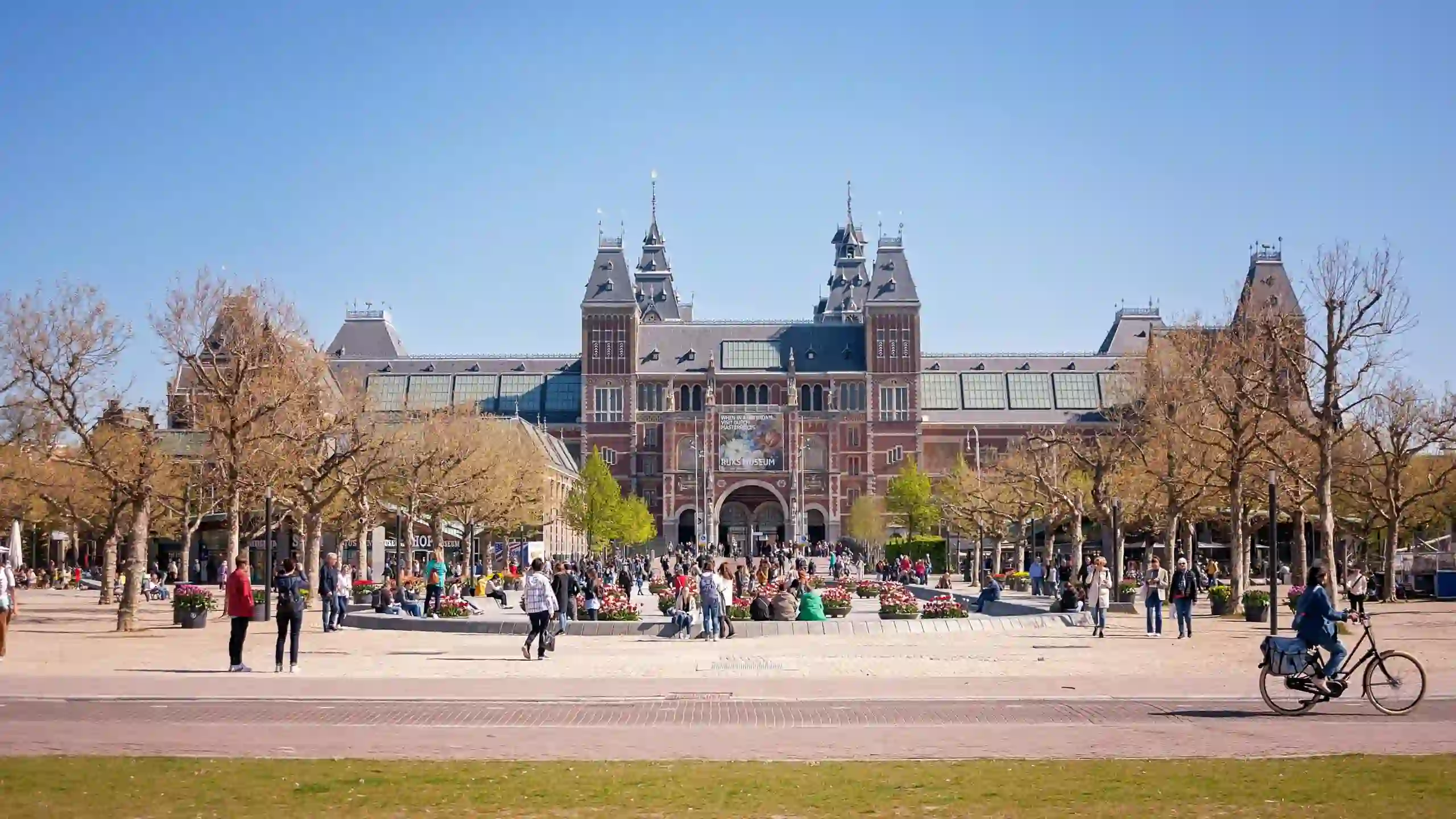 Rijksmuseum em Amesterdão, icónico destino turístico cultural na Holanda, com arquitetura histórica e visitantes na praça ensolarada. Essencial para roteiros de viagem.