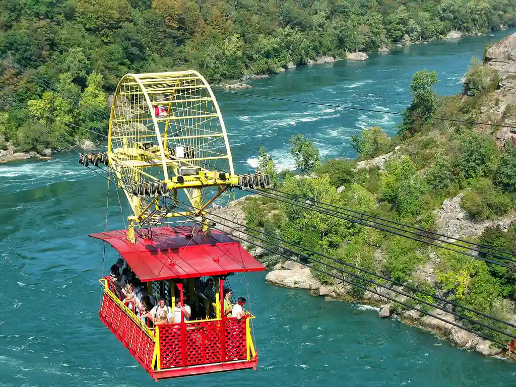 Teleférico com turistas sobre o Rio Niagara, destacando a paisagem natural e atração de aventura para viagens.