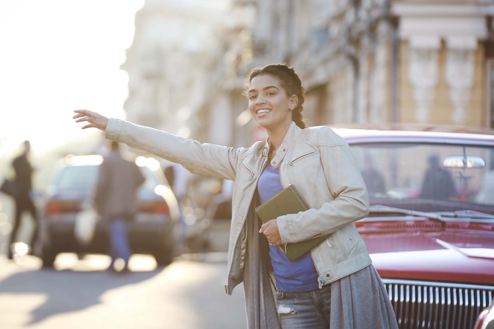 Imagem de uma modelo de pedindo um táxi em paris com o fundo de cidade e carros desfocada de dia 