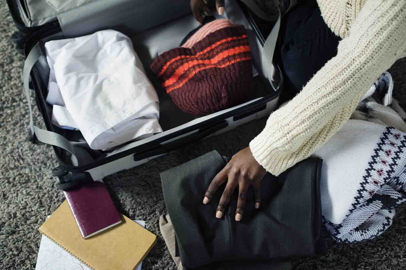 Imagem de uma modelo arrumando a mala, com diversas roupas para o frio 