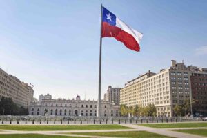 Imagem de uma praça central no Chile, com uma grande bandeira do Chile no centro da imagem e de dia