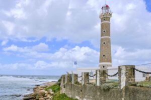 Imagem de um farol em José Ignacio no Uruguai, com o fundo de mar e o céu azul com diversas nuvens.