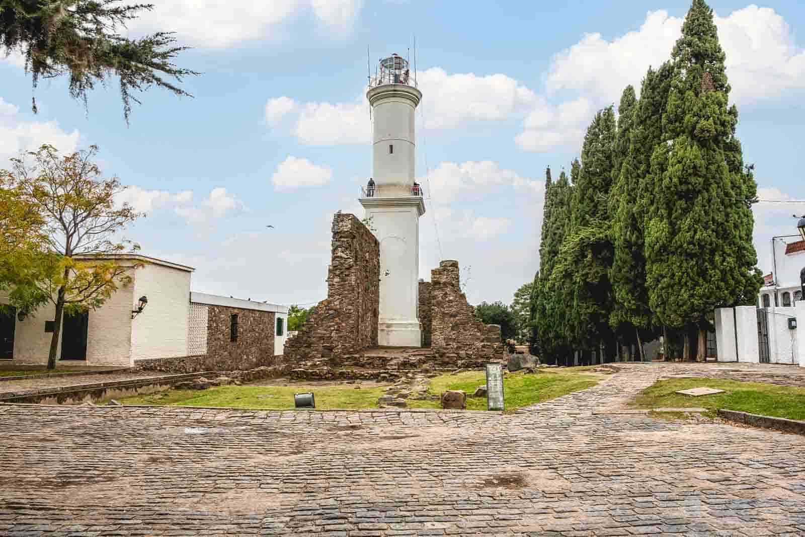 Imagem da Colônia de Sacramento, localizada no Uruguai, com diversas árvores e construções, durante o dia com o céu azul. 