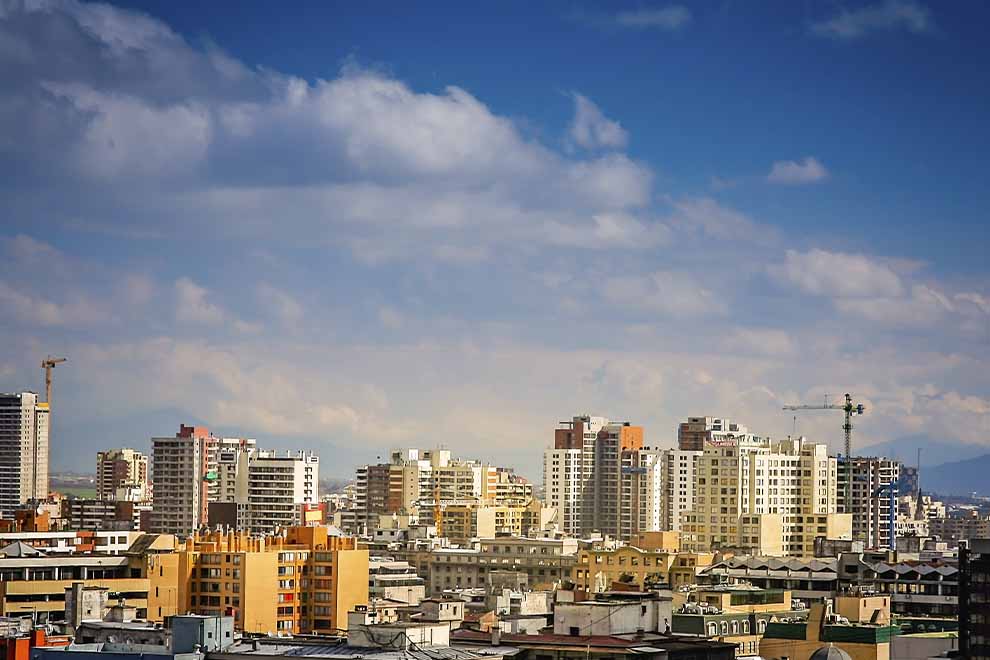 Cidade de Santiago no Chile, com diversos prédios ao fundo, durante o dia com o céu azul. 