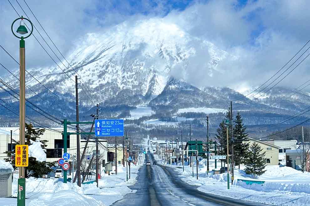 Estrada coberta de neve com montanha ao fundo