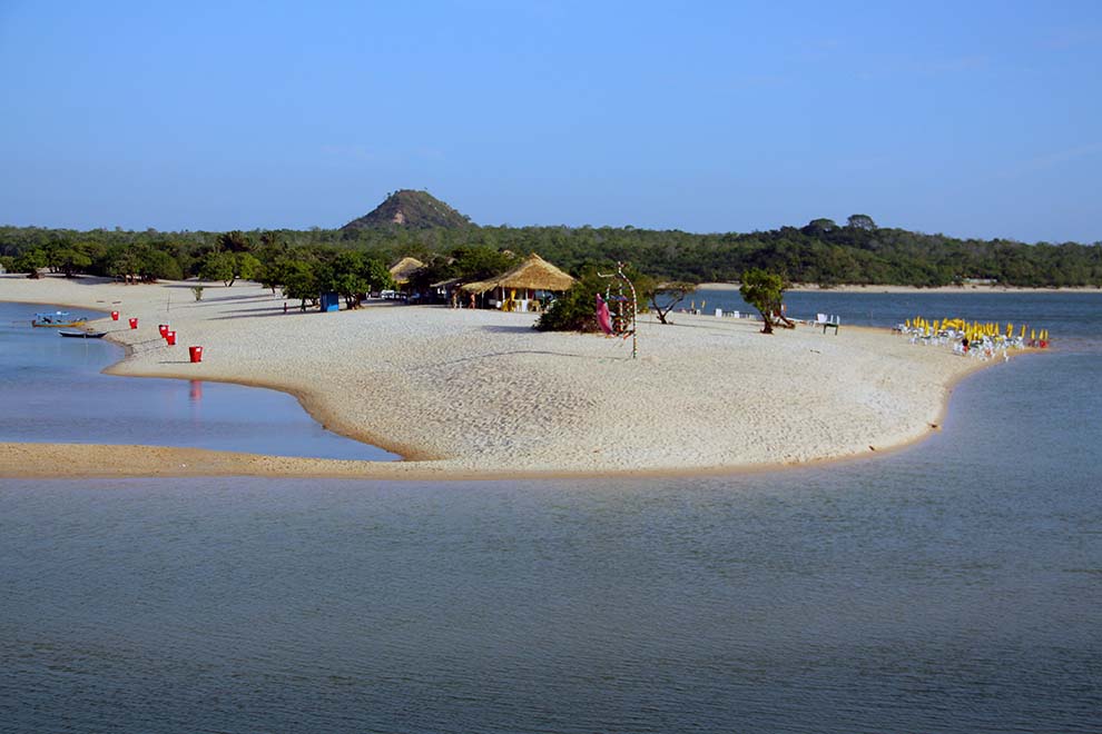 Praia tranquila com ilhas de areia e vegetação ao redor