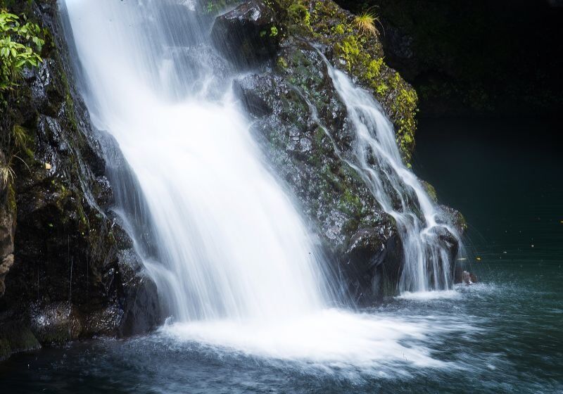 Cascata de água em meio a pedras e vegetação