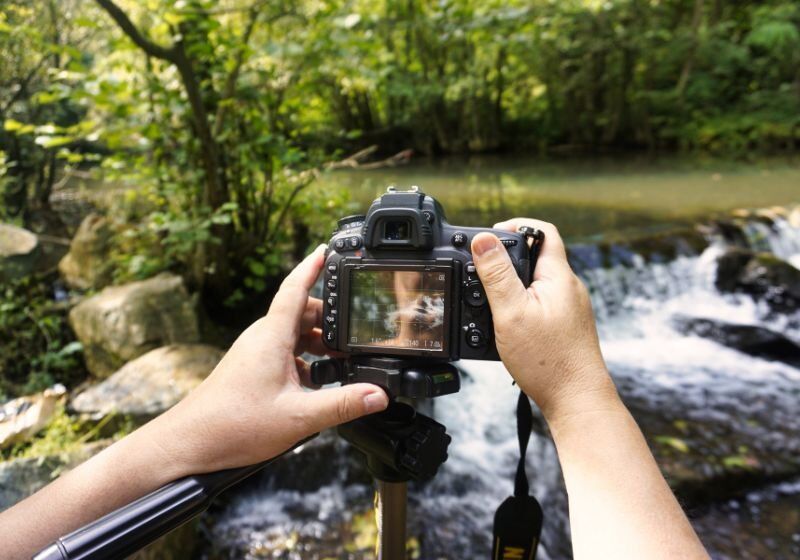 Pessoa fotografando uma cachoeira com DSLR
