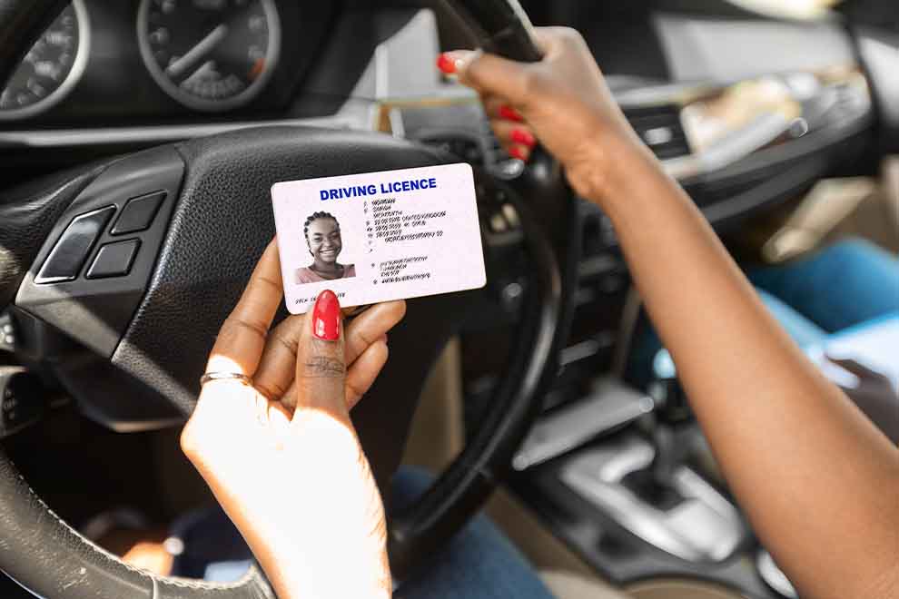 Pessoa segurando carteira de habilitação no carro.