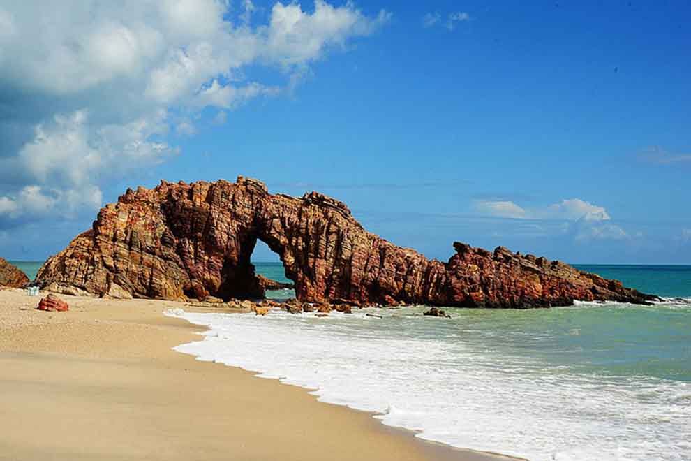 Formação rochosa na praia com mar azul