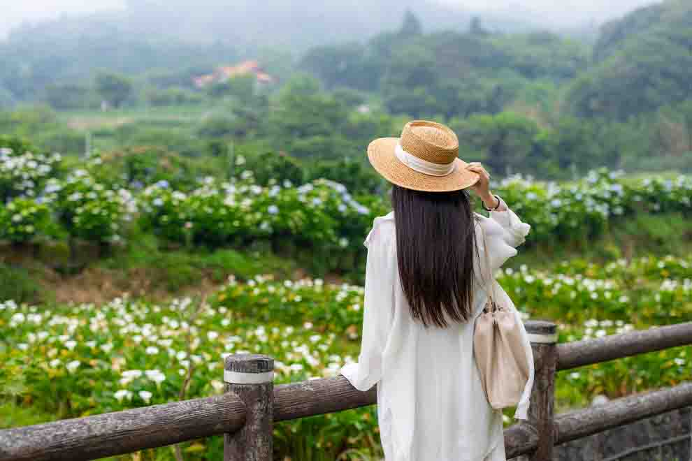 Mulher de chapéu em campo florido