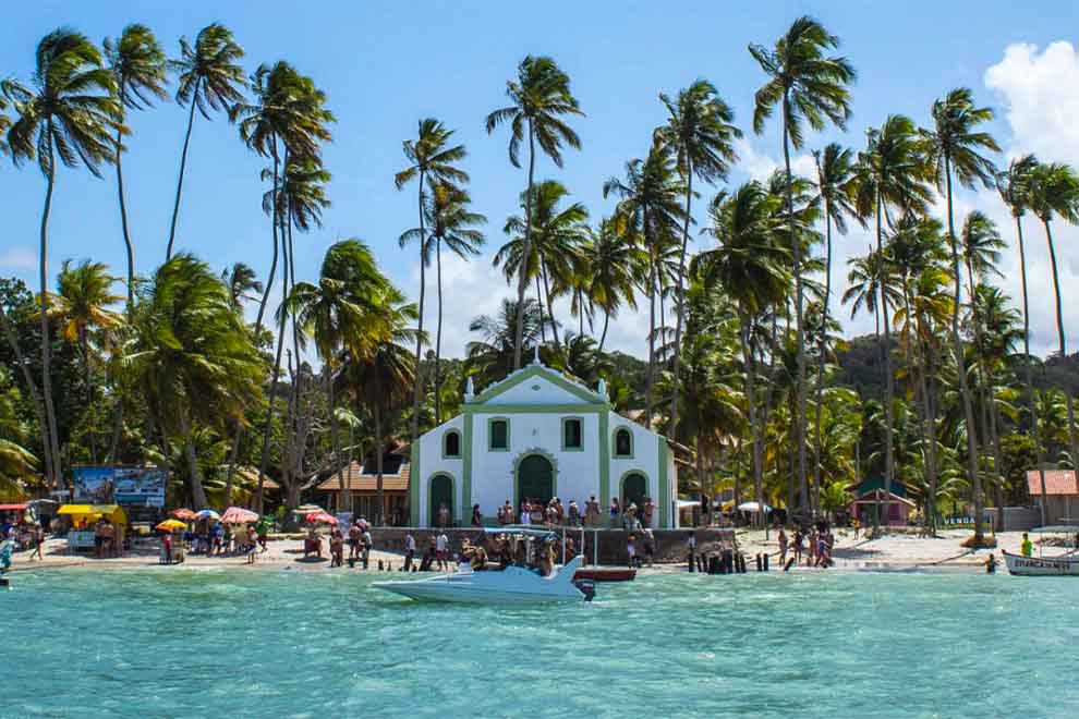 Praia com coqueiros e construções históricas