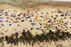 Praia cheia com guarda-sóis coloridos e pessoas relaxando