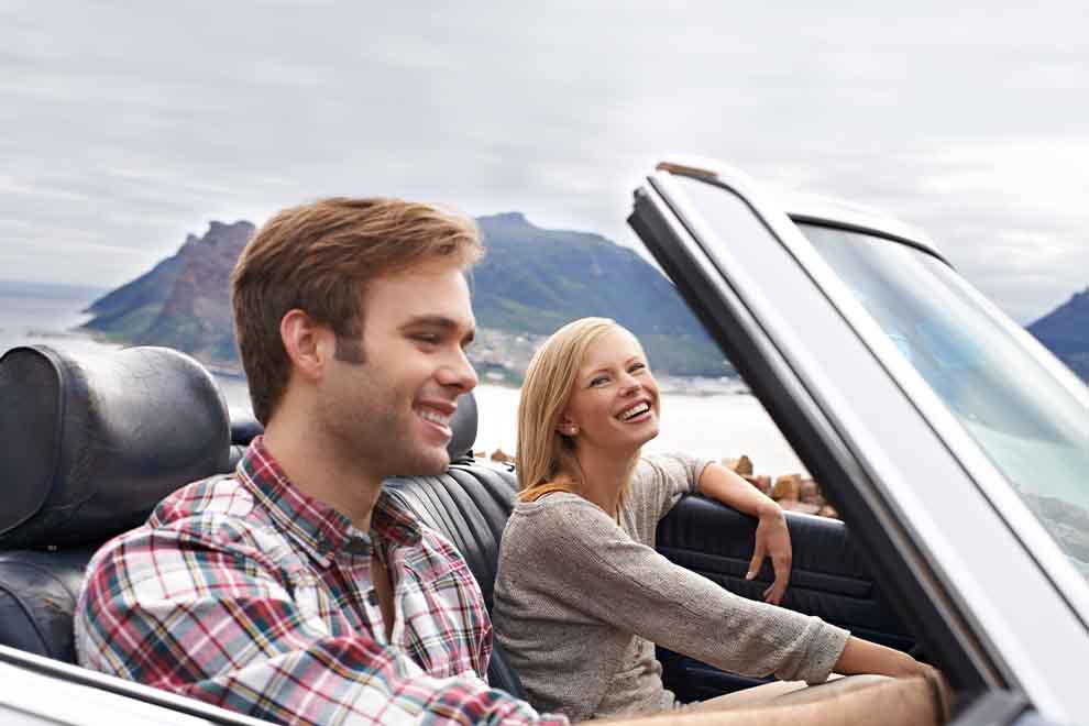 Casal sorridente em um conversível durante passeio