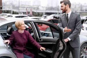 Homem ajudando mulher a sair de carro elegante.