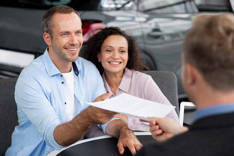 Casal feliz recebendo documentos de venda de carro
