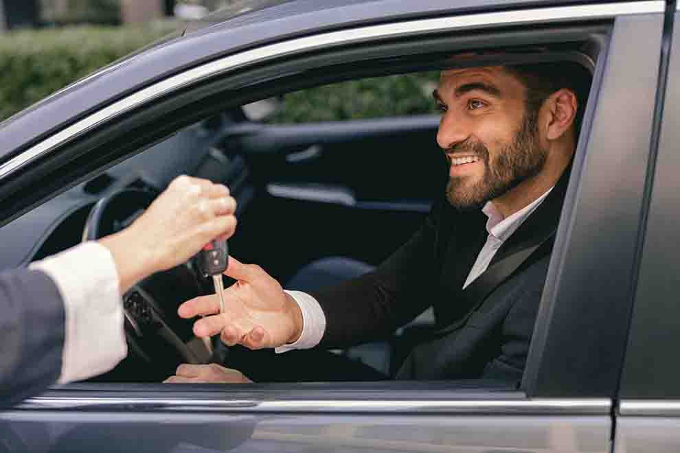 Homem sorridente recebendo chave de carro