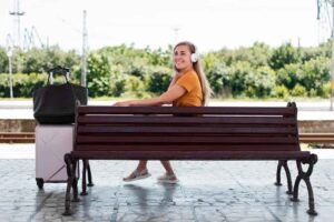 Jovem escutando música em banco na estação