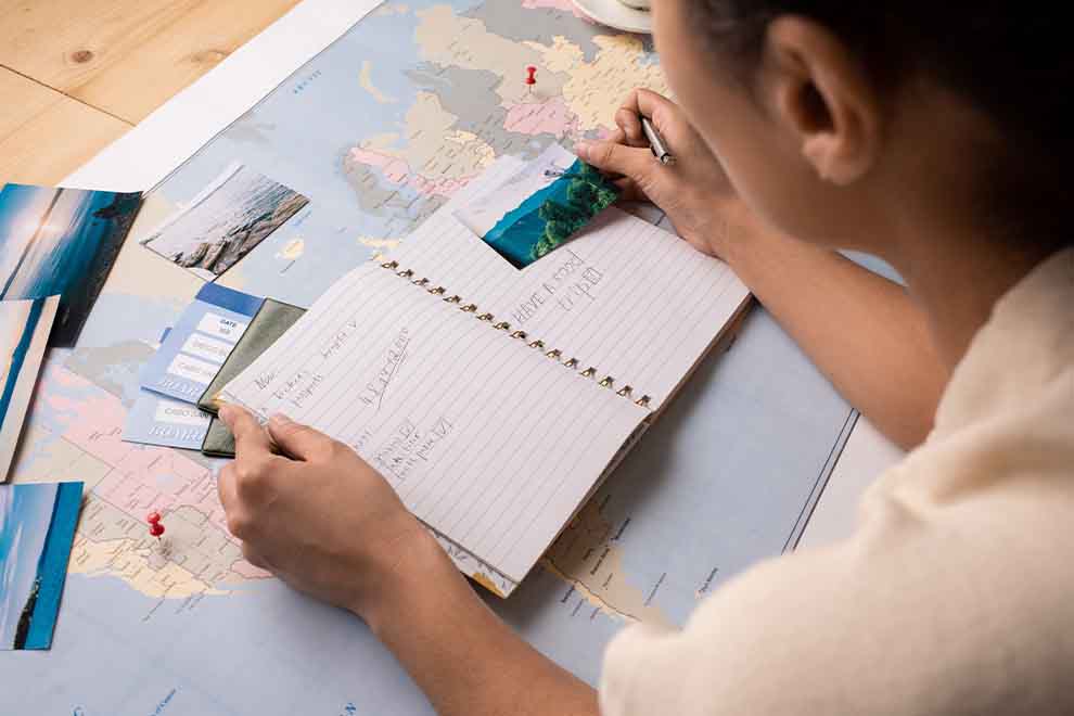 Pessoa escrevendo em caderno sobre viagem