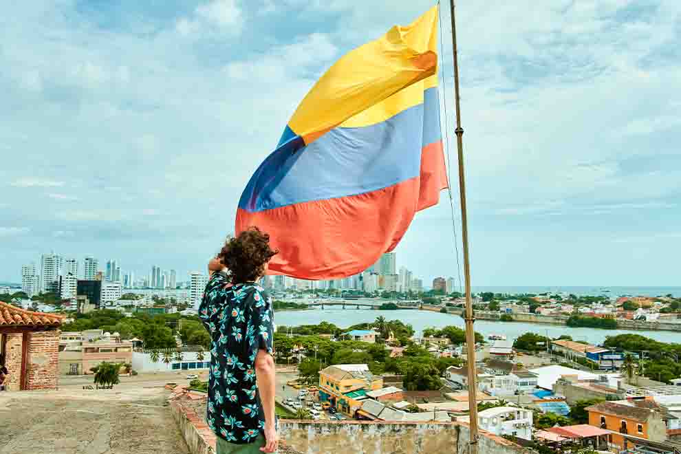 Homem segurando bandeira da Colômbia em vista urbana