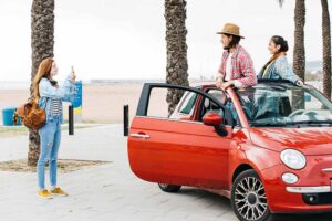 Casal e amiga em carro vermelho em passeio