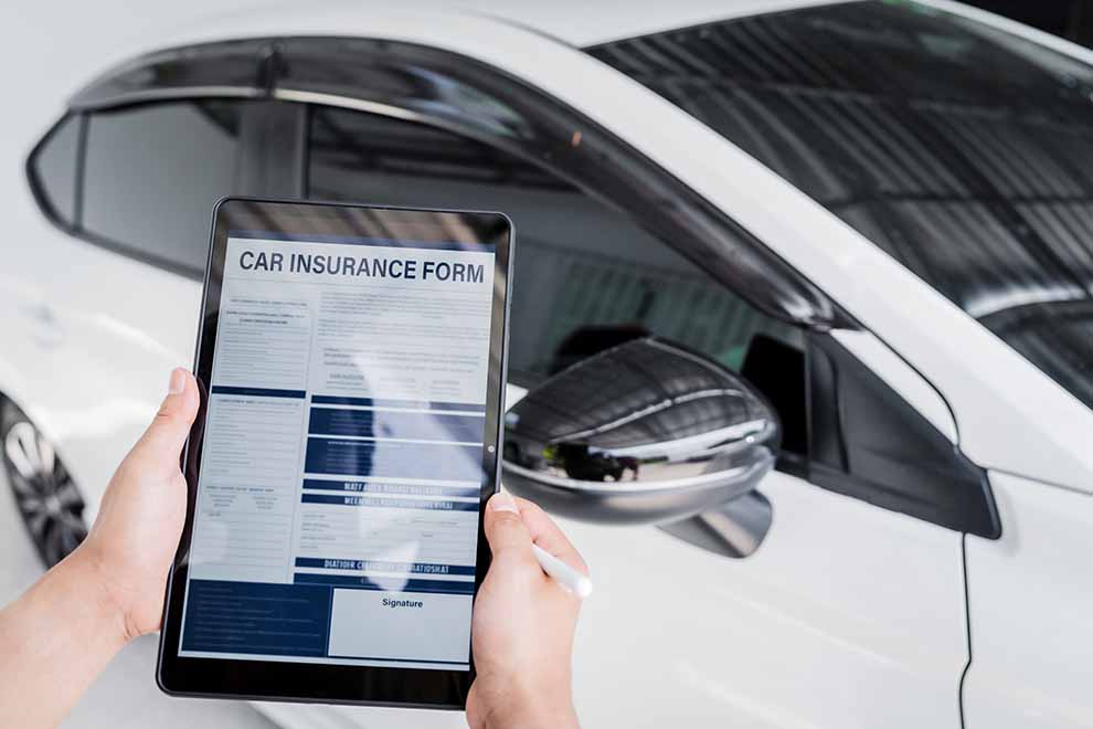 Homem segurando tablet com formulário de seguro de carro.