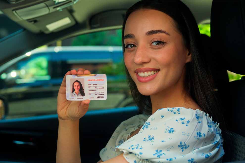 Mulher sorrindo com a carteira de motorista na mão.