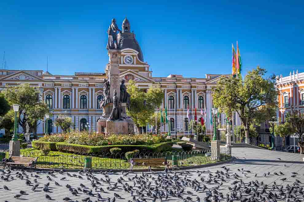 Praça central com monumento e pombos em La Paz