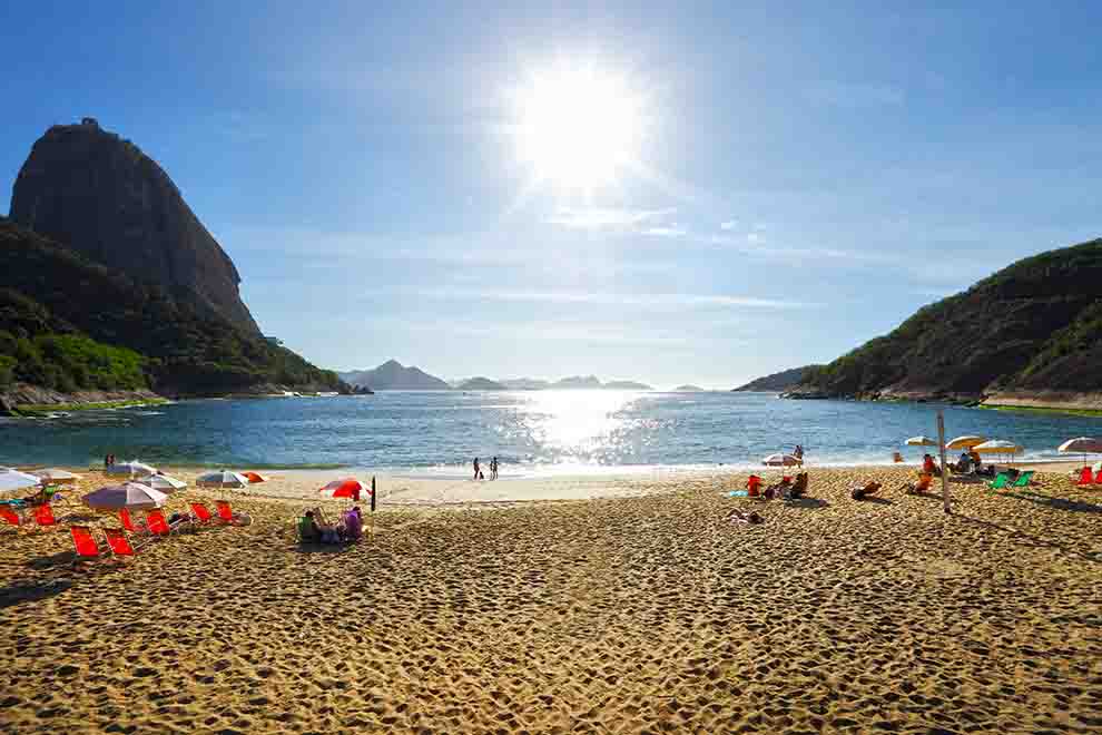 Praia com sol brilhante e montanhas ao fundo