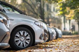 Carros estacionados em rua coberta de folhas