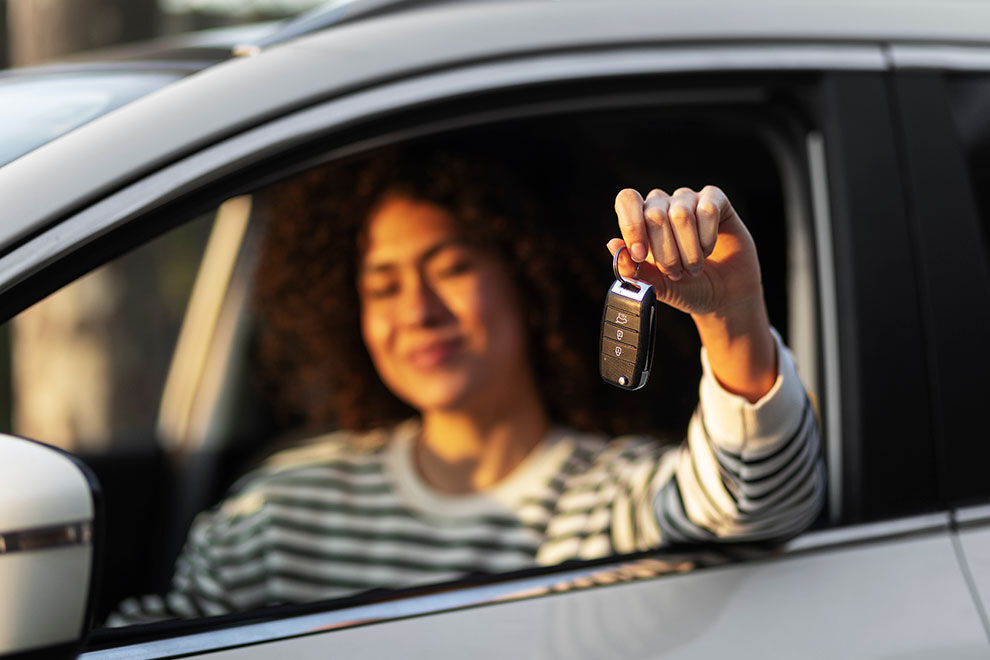 Pessoa feliz segurando chave de carro na janela