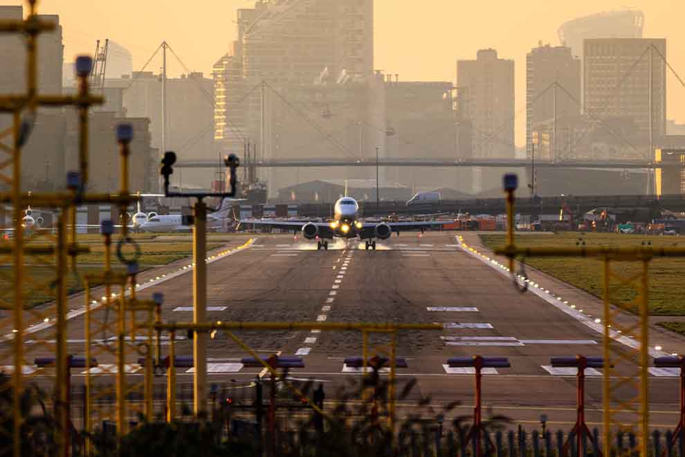 Avião pousando em pista de aeroporto ao entardecer.