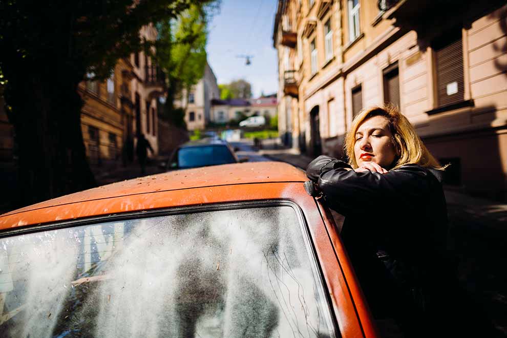 Mulher encostada em carro antigo na rua