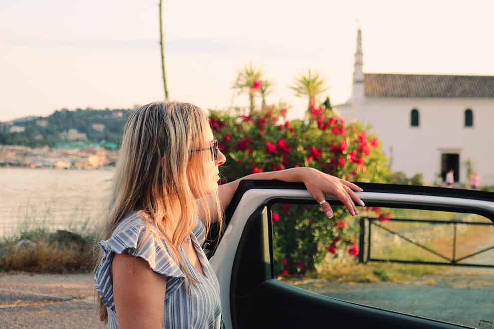 Mulher sorrindo ao lado de carro em paisagem tranquila